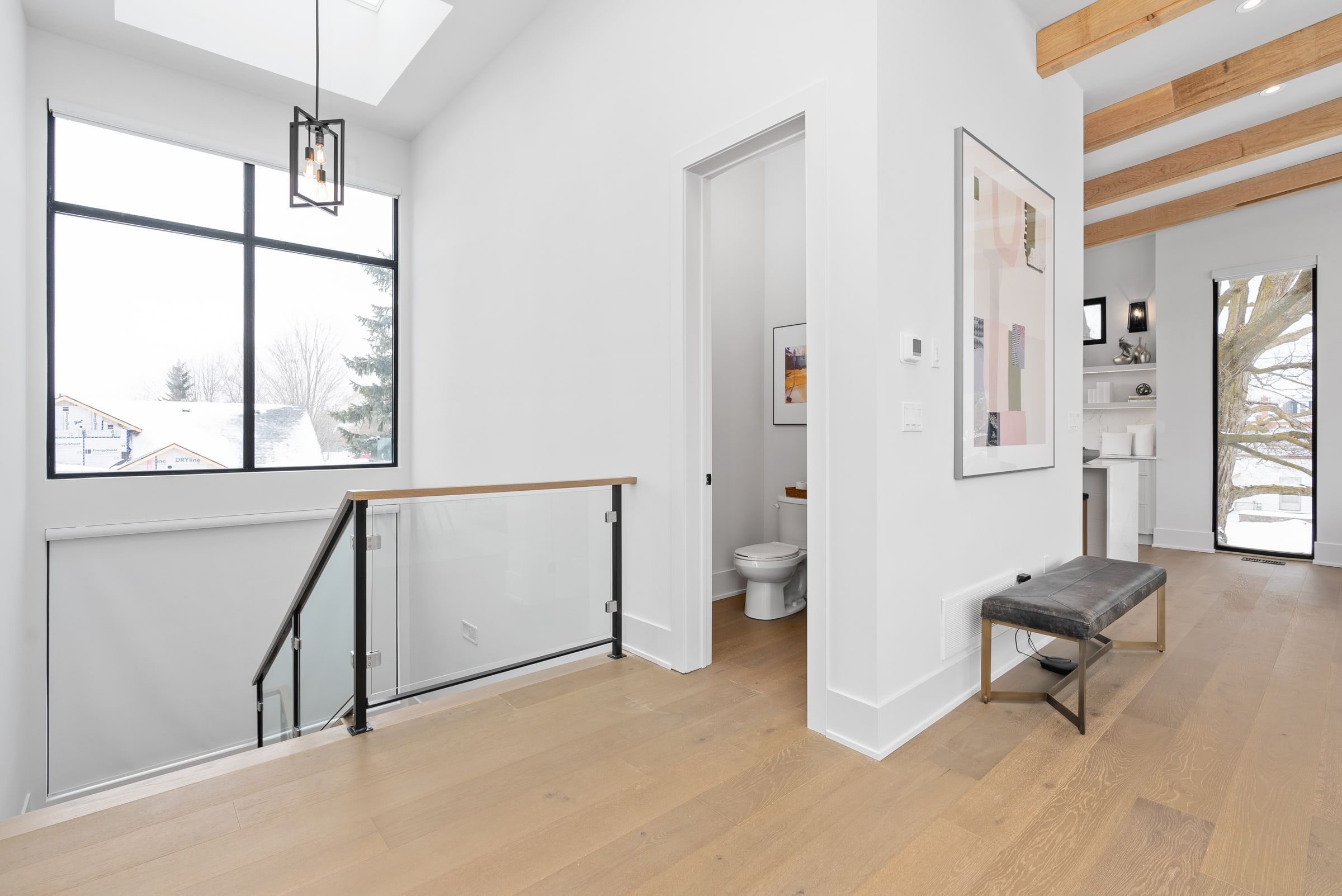Upper landing with a glass-panel railing beneath the vaulted ceiling.